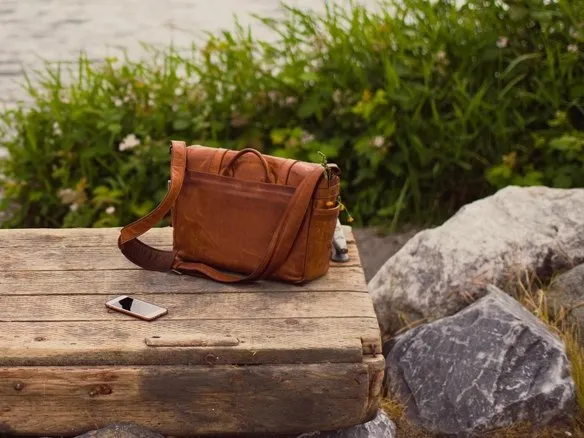 A brown leather messenger bag on a wooden crate